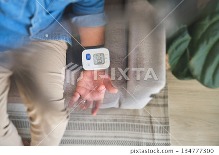 Person checking blood pressure at home with wrist monitor Person checking blood pressure at home with wrist monitor 134777300