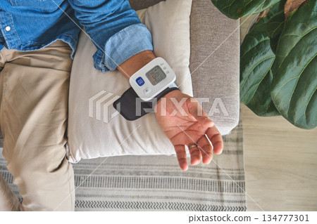 Person checking blood pressure at home with wrist monitor 134777301