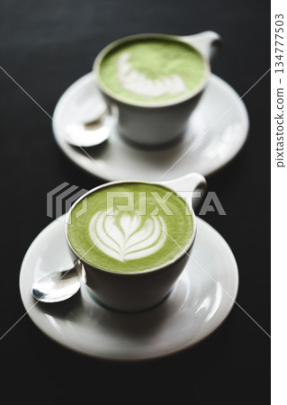 Two cups of matcha latte on black table Two cups of matcha latte on black table 134777503