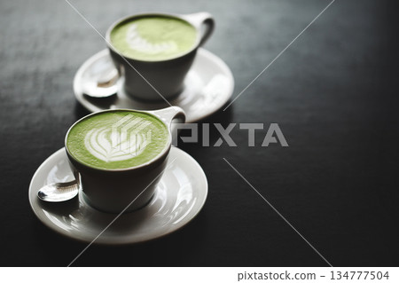Two cups of matcha latte on black table Two cups of matcha latte on black table 134777504
