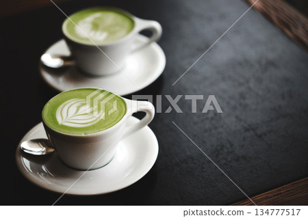 Two cups of matcha latte on black table Two cups of matcha latte on black table 134777517