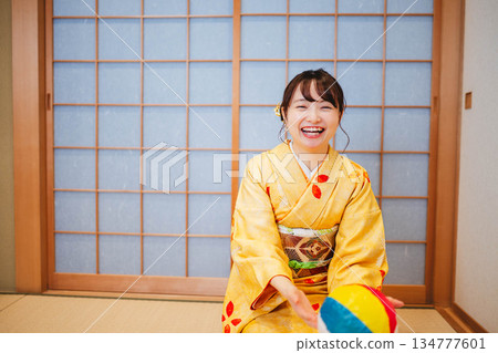 A beautiful young woman in a kimono playing with paper balloons A beautiful young woman in a kimono playing with paper balloons 134777601