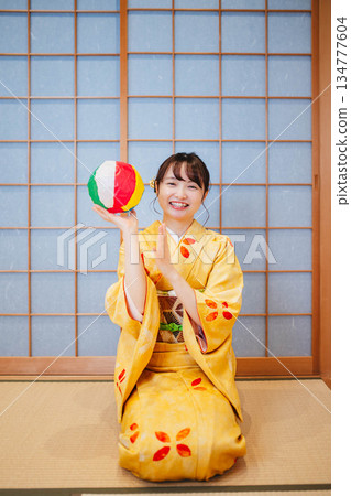 A beautiful young woman in a kimono playing with paper balloons A beautiful young woman in a kimono playing with paper balloons 134777604