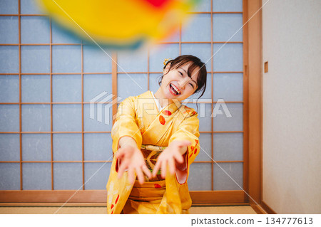 一位身穿和服的美麗年輕女子在玩紙氣球 一位身穿和服的美麗年輕女子在玩紙氣球 134777613