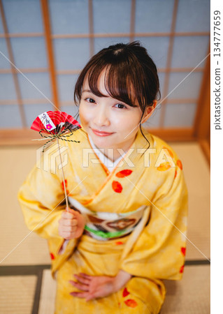 一位年輕貌美的身著和服的女子手捧新年裝飾品 134777659