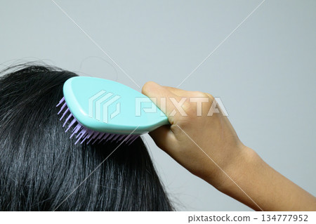 Woman's hands combing her hair with a hairbrush 134777952