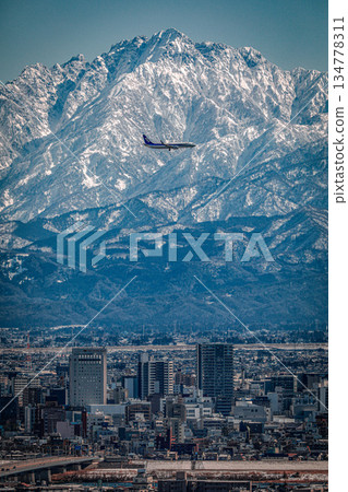 一架飛機飛越高地，背景是立山山脈。 134778311