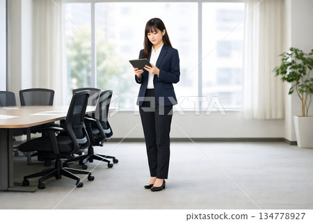 會議期間，一位女領袖正在查看平板電腦。 134778927