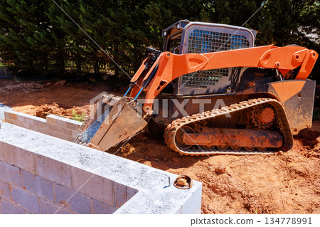 Construction machine is on site pushing gravel near concrete blocks Construction machine is on site pushing gravel near concrete blocks 134778991