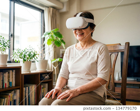一位微笑的老婦人戴著VR眼鏡，正在享受虛擬實境。 134779170