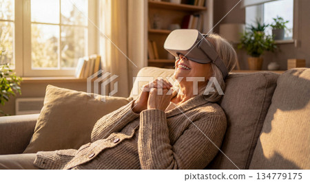 一位微笑的老婦人戴著VR眼鏡，正在享受虛擬實境。 134779175