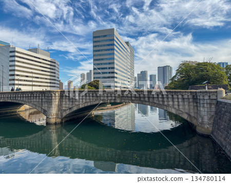 Stone arch bridge and urban buildings reflected on the canal water surface 2025.11.12 Hamarikyu, Japan 134780114