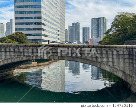 Stone arch bridge and urban buildings reflected on the canal water surface 2025.11.12 Hamarikyu, Japan 134780116