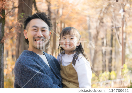 Image of family outings and leisure activities playing in a park with roadside trees in autumn and winter. Close-up of smiling upper body looking at camera 134780631