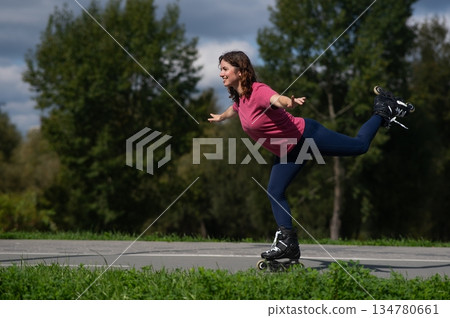 Caucasian woman roller skating in park. Caucasian woman roller skating in park. 134780661
