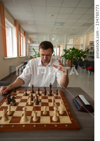 Middle aged Caucasian man playing chess.  134780773