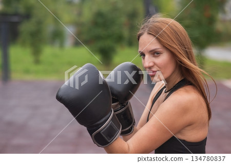 A Caucasian woman practices boxing outdoors. A Caucasian woman practices boxing outdoors. 134780837