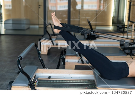 Caucasian woman doing exercises on reformer machine.  134780887