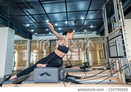 Caucasian woman doing exercises on reformer machine. Caucasian woman doing exercises on reformer machine. 134780888