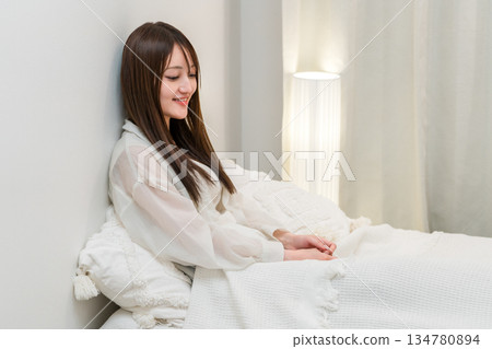 一位年輕的亞洲女性在夜裡放鬆地躺在床上 一位年輕的亞洲女性在夜裡放鬆地躺在床上 134780894
