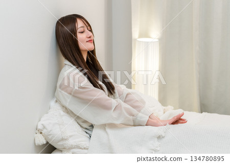 一位年輕的亞洲女性在夜裡放鬆地躺在床上 一位年輕的亞洲女性在夜裡放鬆地躺在床上 134780895