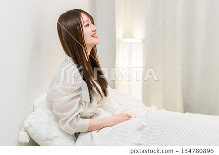 A young Asian woman relaxing in bed at night A young Asian woman relaxing in bed at night 134780896