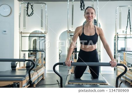 Caucasian woman doing exercises on reformer machine.  134780909
