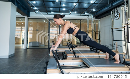 Caucasian woman doing exercises on reformer machine.  134780945