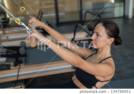 Caucasian woman doing exercises on reformer machine.  134780951
