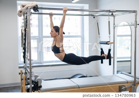 Caucasian woman doing pilates on reformer.  134780963