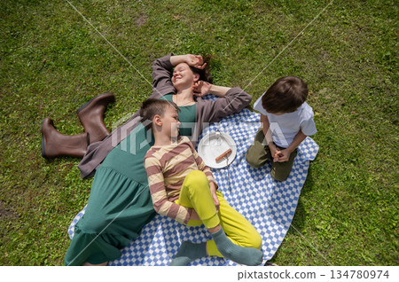 Caucasian woman eats fried sausages with her sons at a picnic. Caucasian woman eats fried sausages with her sons at a picnic. 134780974