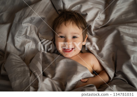 Top view of cute caucasian toddler lying in bed. Top view of cute caucasian toddler lying in bed. 134781031