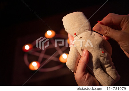 Woman sticking pins into voodoo doll.  134781079