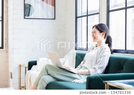 使用一台電腦在客廳裡的年輕女子 134781330