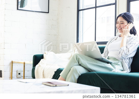 Young woman using a computer in the living room Young woman using a computer in the living room 134781361