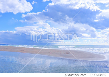 A lagoon and ocean in the daytime with blue sky and clouds; a quiet sandy beach A lagoon and ocean in the daytime with blue sky and clouds; a quiet sandy beach 134783492