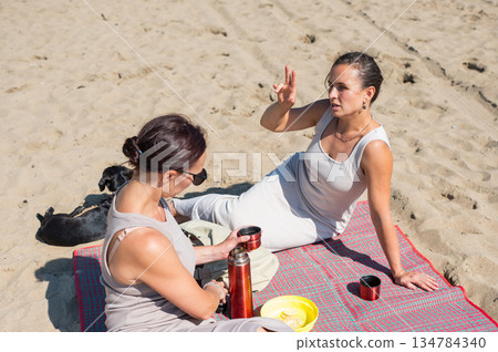 Two Caucasian women on a picnic on the beach.  134784340