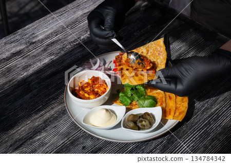A chef wearing black gloves prepares fajitas. A chef wearing black gloves prepares fajitas. 134784342