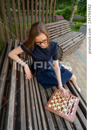 Caucasian woman playing chess outdoors. 134784362
