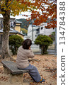 A middle-aged woman sitting alone on a bench in an autumn park A middle-aged woman sitting alone on a bench in an autumn park 134784388