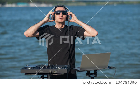 Male DJ playing music on the beach. Male DJ playing music on the beach. 134784390