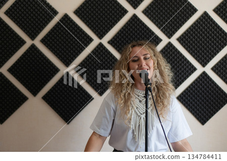 Caucasian woman singing into microphone in music studio. Caucasian woman singing into microphone in music studio. 134784411