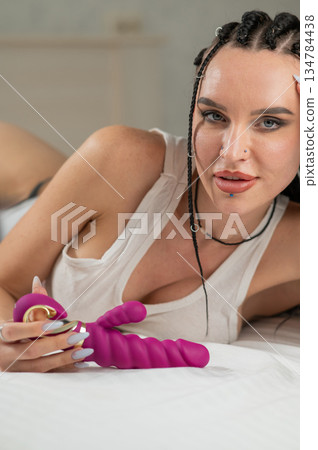 Portrait of Caucasian woman lying on bed among sex toys.  134784438