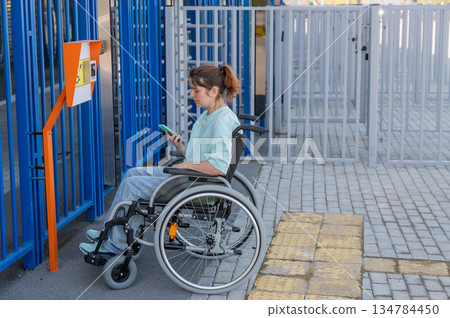 A woman in a wheelchair uses a call button for people with disabilities. 134784450