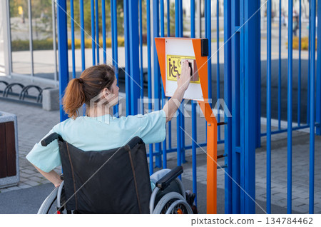 A woman in a wheelchair uses a touch-sensitive Braille help button..  134784462