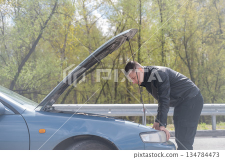Caucasian man looking under the hood of his car.  134784473