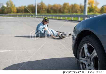 A Caucasian woman on a scooter after being hit by a car. 134784478