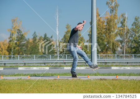 A Caucasian man rollerblades around the slalom course. A Caucasian man rollerblades around the slalom course. 134784525