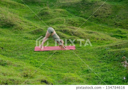 Caucasian woman doing yoga outdoors. Downward facing dog. Caucasian woman doing yoga outdoors. Downward facing dog. 134784616