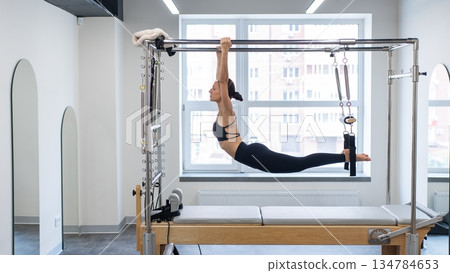 Caucasian woman doing pilates on reformer. Caucasian woman doing pilates on reformer. 134784653